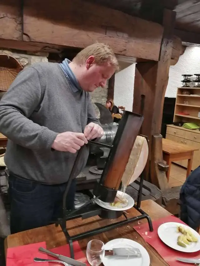 Alexander Whaley in Frangy, Pays de Gex, France. Trying out a modern raclette machine, capable of holding a 1/2 wheel of cheese. A specialty of the restaurant.