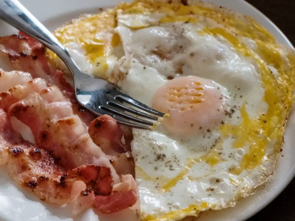 3 rashers of streaky bacon with 1 egg on a plate