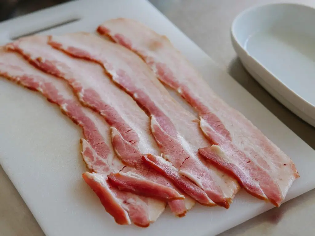 Raw streaky bacon, 4 rashers on a chopping board