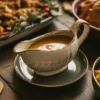 Sumptuous gravy in a gravy boat surrounded by thanksgiving favourites