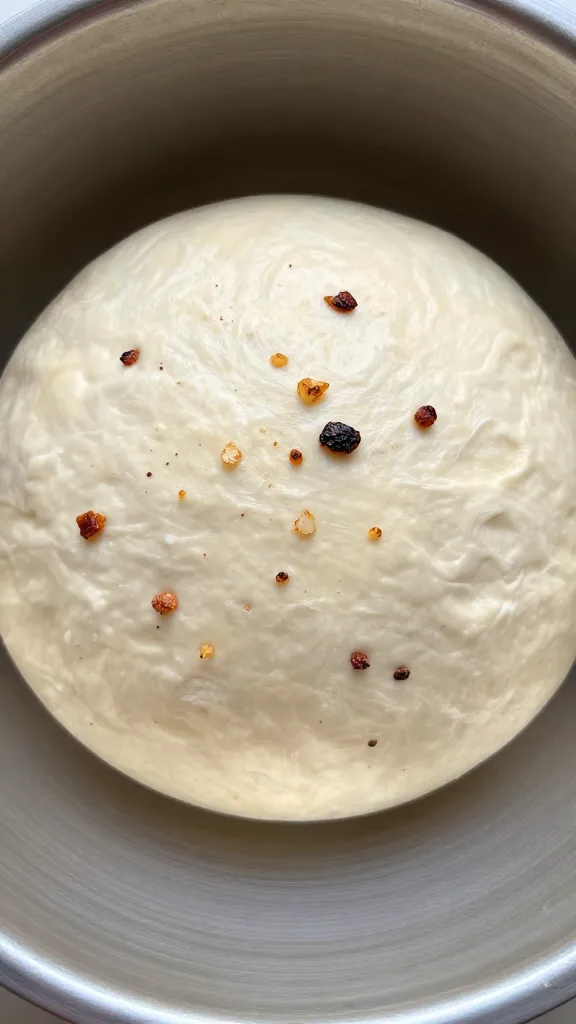 dough ball studded with roasted garlic, proofing in bowl