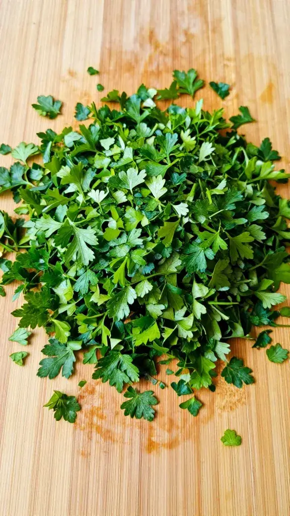 finely chopped flat-leaf parsley on wooden cutting board