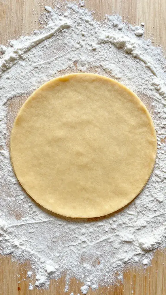 single puff pastry round cutout on floured board