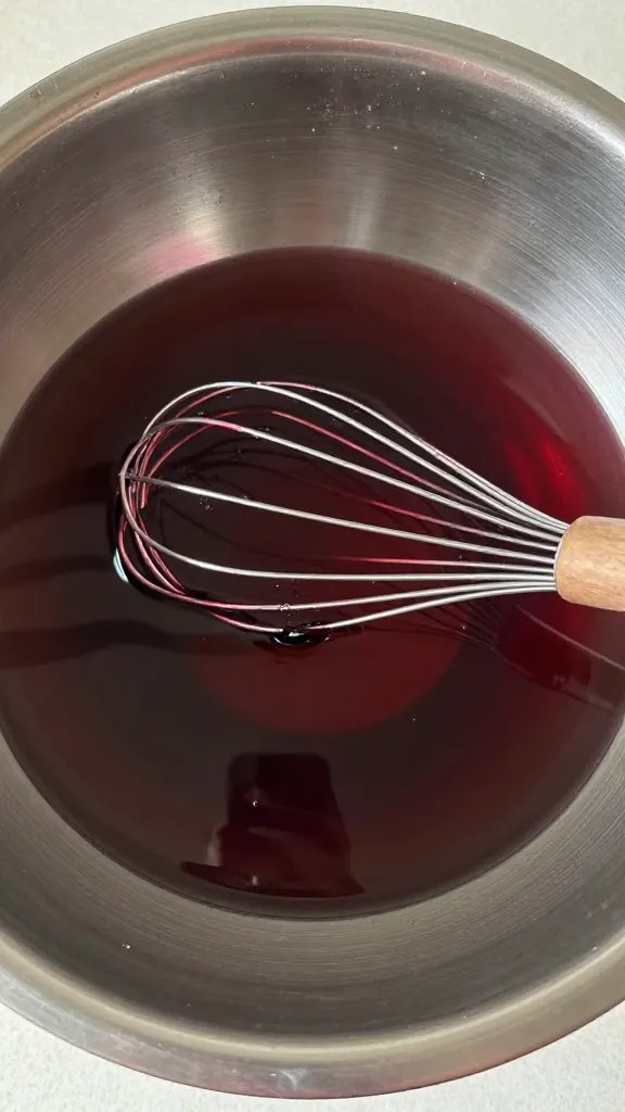 Stainless bowl of red wine garlic marinade, whisk inside