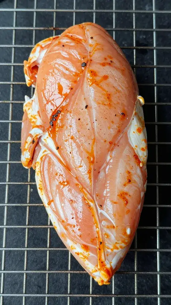 single marinated chicken breast on wire rack