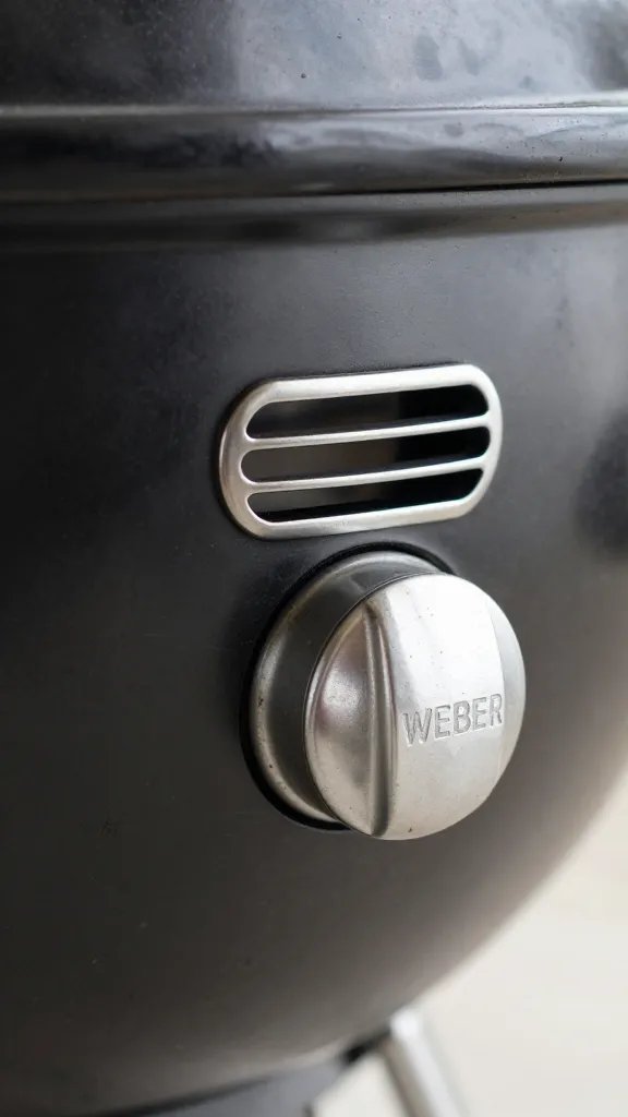 single Weber kettle grill vent dial set to half-open