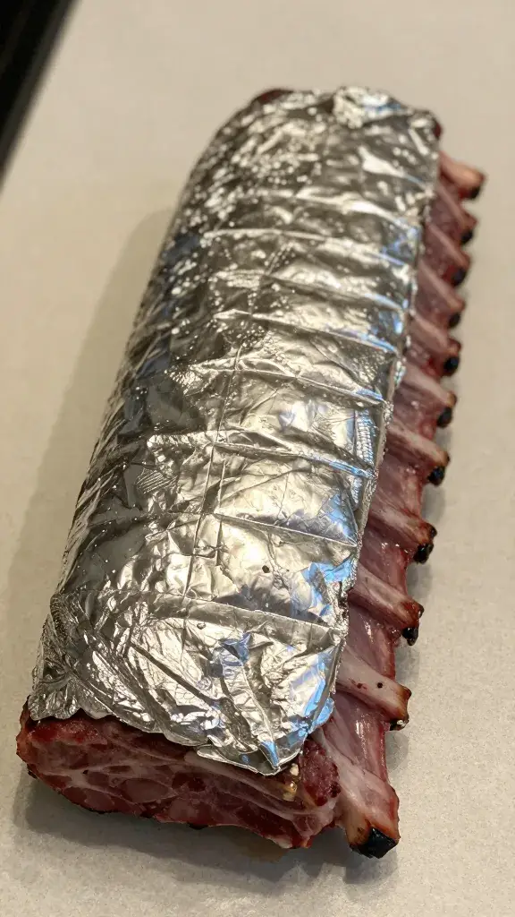 Foil-wrapped rib slab resting on countertop, tight shot