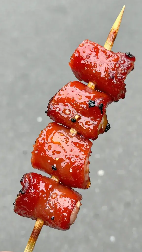 closeup of charred pork skewer with glossy red sheen