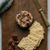 Cheese ball coated in pecans and cranberries on rustic board
