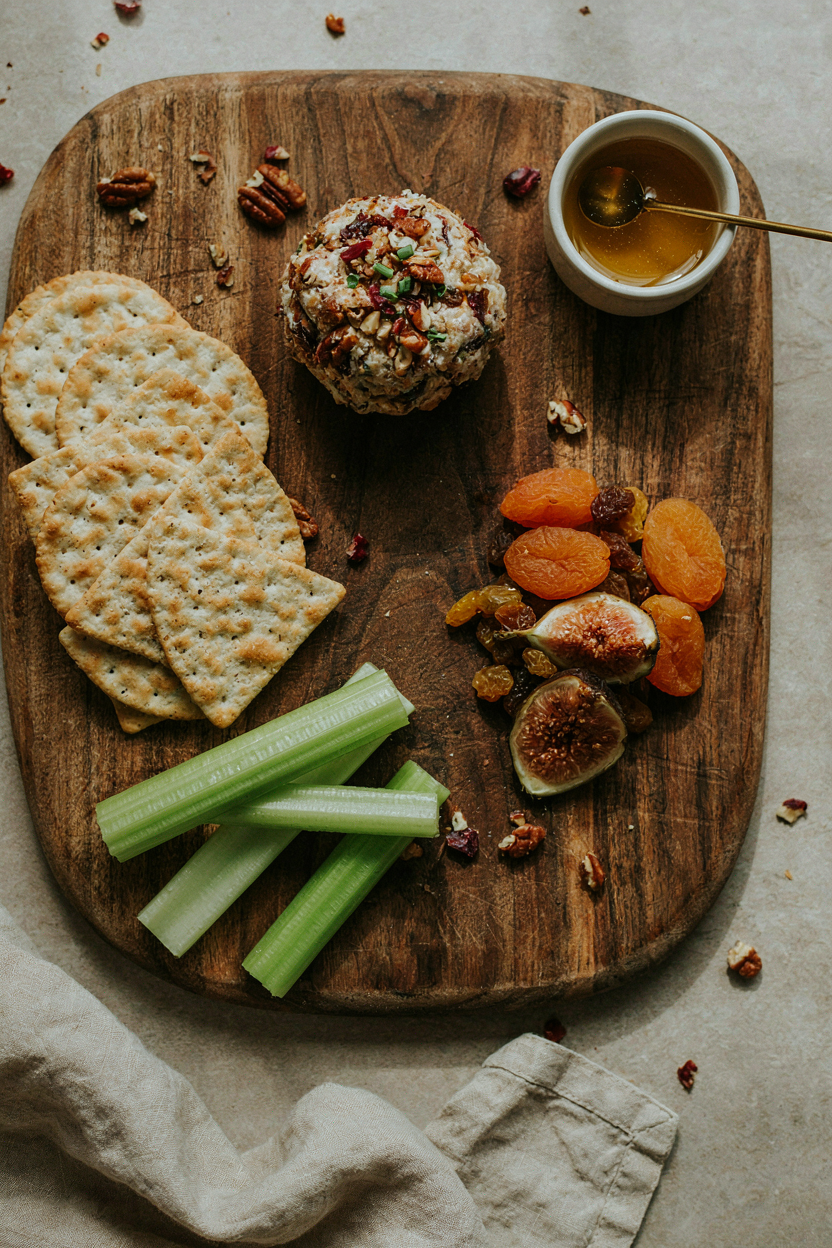 Finished cheese ball on serving board with crackers and fruit