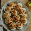 Platter of deviled eggs with piped filling and paprika