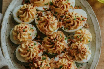 Platter of deviled eggs with piped filling and paprika