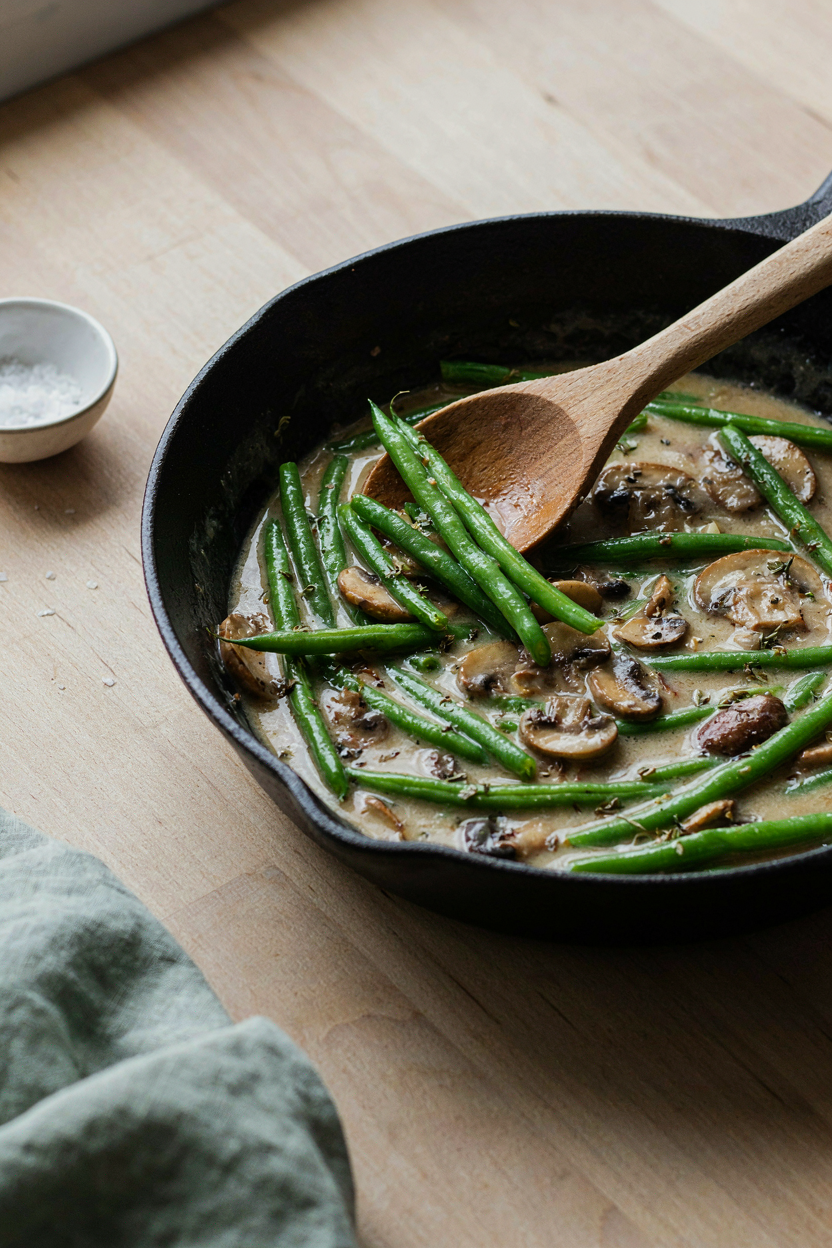 Bright green beans being folded into creamy mushroom sauce