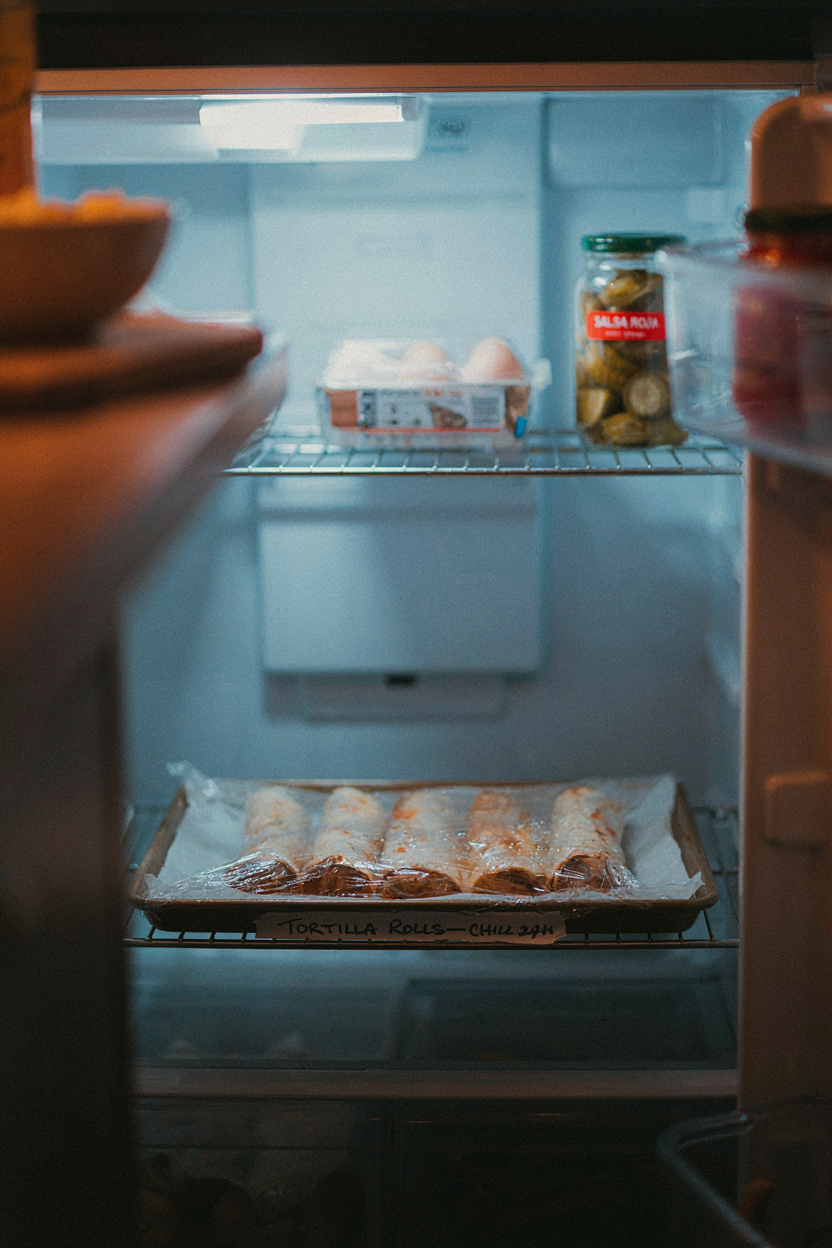 Tortilla logs wrapped in plastic wrap on baking sheet