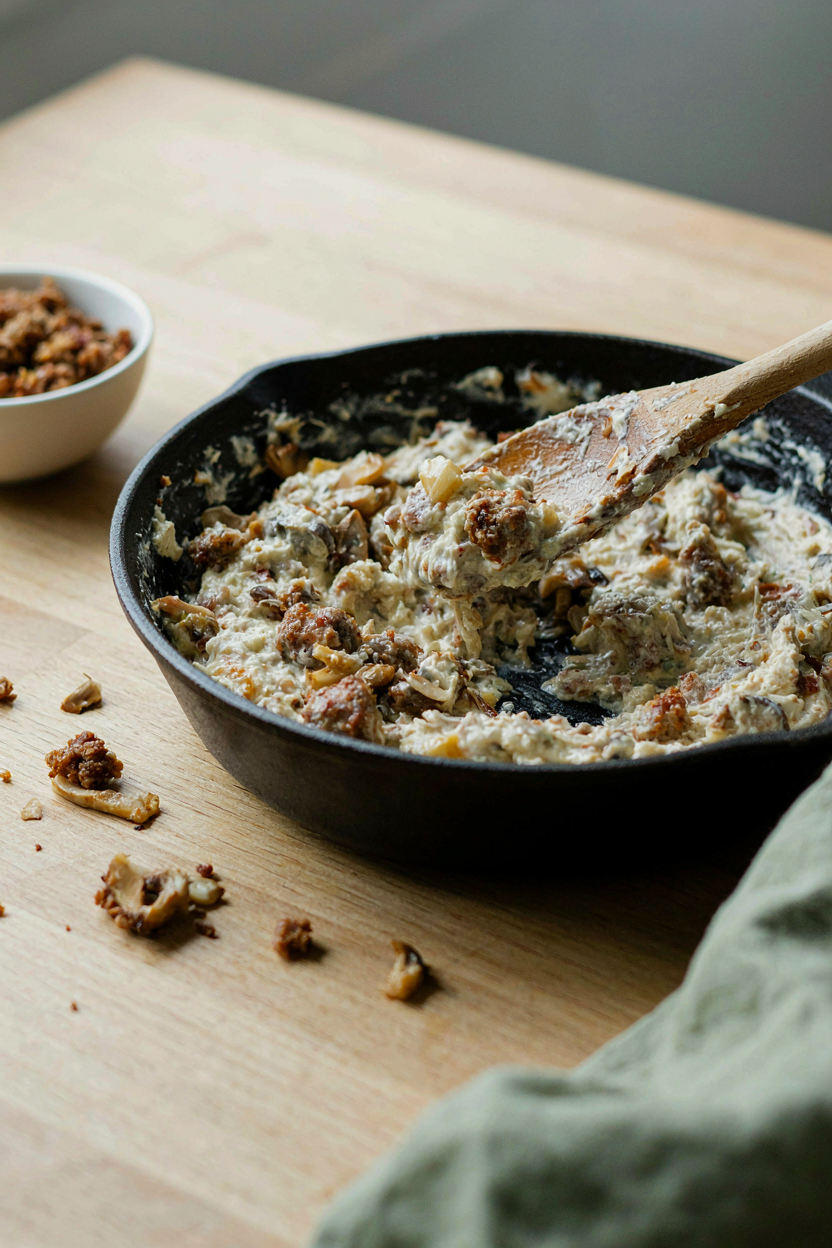Cream cheese and sausage filling being mixed in skillet