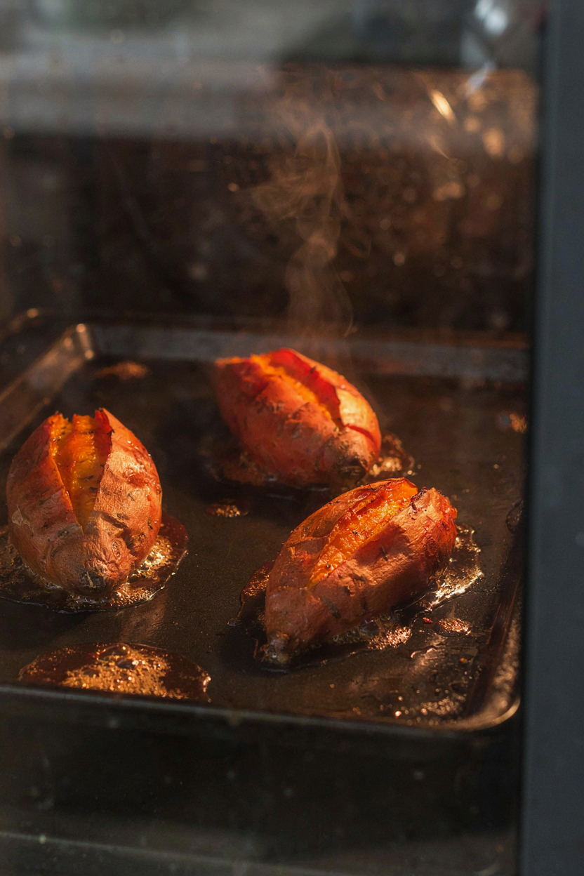 Sweet potatoes roasting on baking sheet in oven
