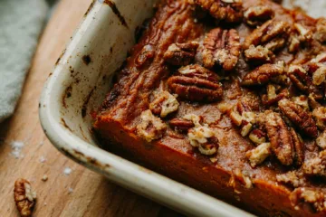 Corner of baking dish showing sweet potato filling under pecan streusel