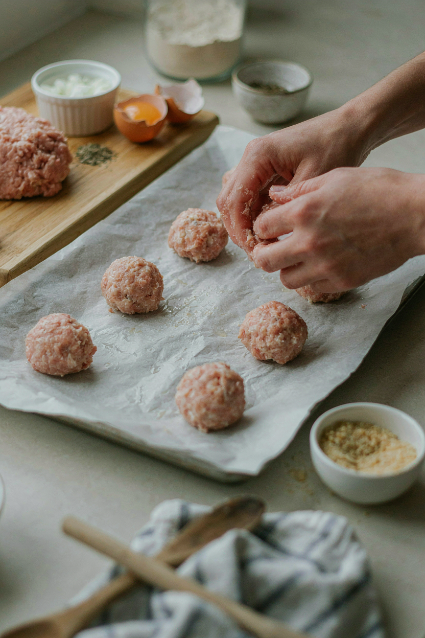 Hands rolling turkey meatball mixture into small round balls